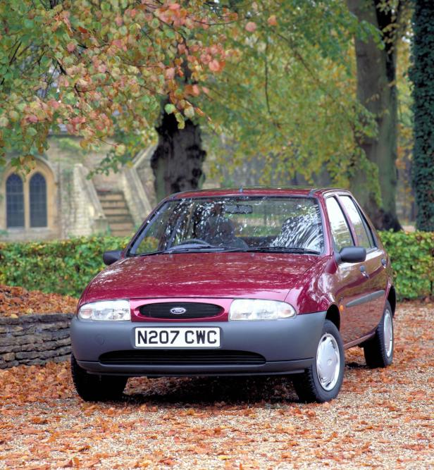 Ein roter Ford Fiesta der vierten Generation vor einem herbstlichen Hintergrund.