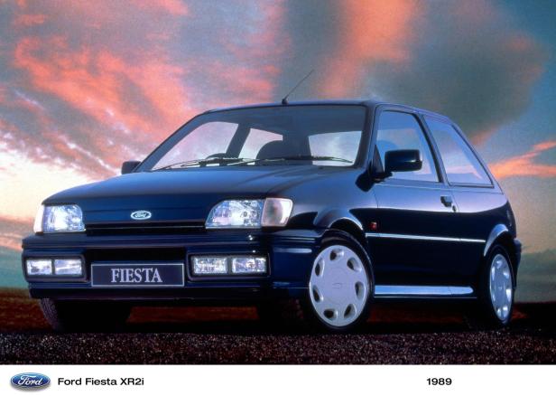 Ein dunkelblauer Ford Fiesta XR2i des Baujahrs 1989 vor einem bewölkten Himmel.