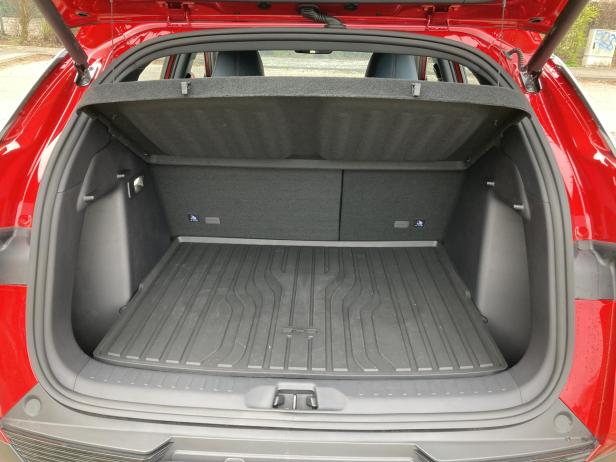 Der offene Kofferraum eines roten Autos mit einer schwarzen Gummimatte.