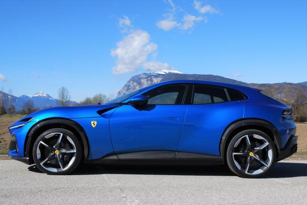 Ein blauer Ferrari Purosangue vor einer Bergkulisse.