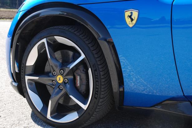 Detailaufnahme eines blauen Ferraris mit Felge, Reifen und dem Ferrari-Logo.
