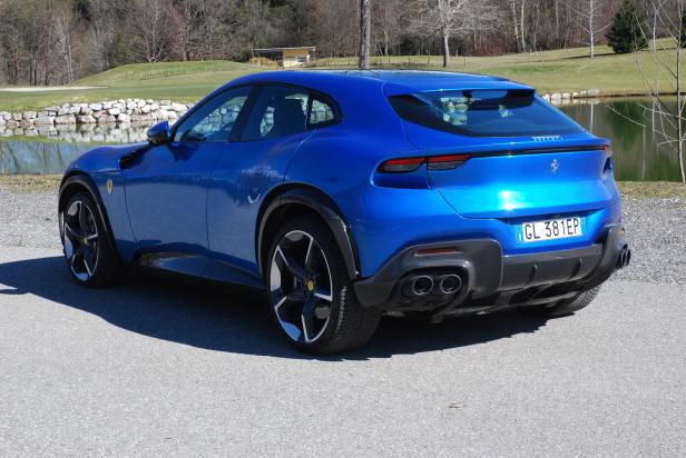 Ein blauer Ferrari Purosangue steht auf einer Straße.