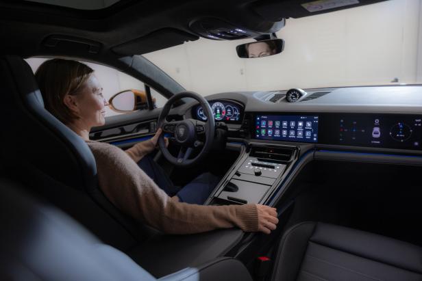 Eine Frau sitzt am Steuer eines modernen Porsche-Modells.