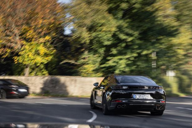 Ein schwarzer Porsche fährt auf einer kurvigen Straße.