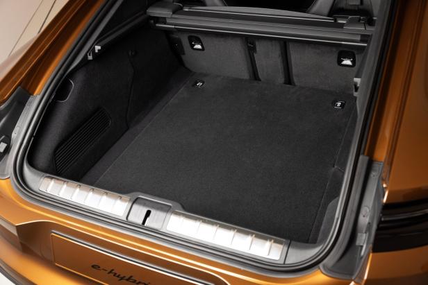 Der leere Kofferraum eines goldfarbenen Autos mit schwarzem Teppichboden.