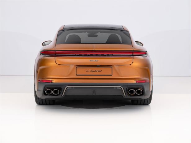 Die Rückansicht eines bronzefarbenen Porsche Panamera Turbo S E-Hybrid vor einem weißen Hintergrund.