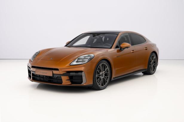 Ein orangefarbener Porsche Panamera e-Hybrid steht in einem Studio.