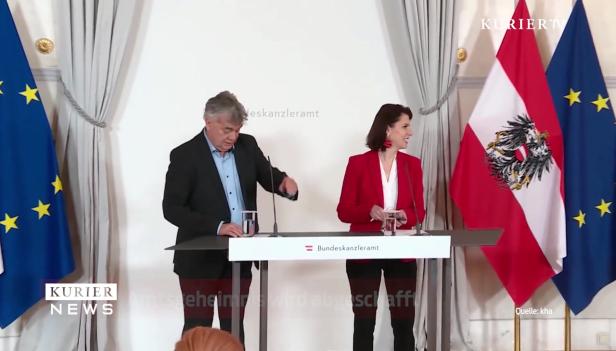 Ein Mann und eine Frau stehen an einem Rednerpult vor österreichischen und EU-Flaggen.