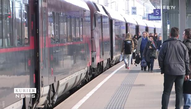 Menschen steigen an einem Bahnhof in einen Zug ein.