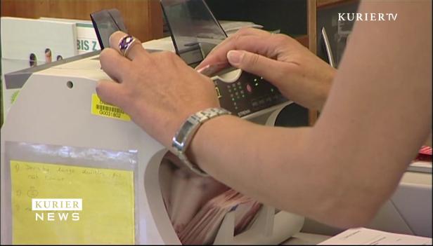 Eine Person bedient eine Geldzählmaschine.