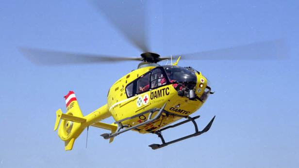 Ein gelber ÖAMTC Hubschrauber fliegt über einem wolkenlosen Himmel.