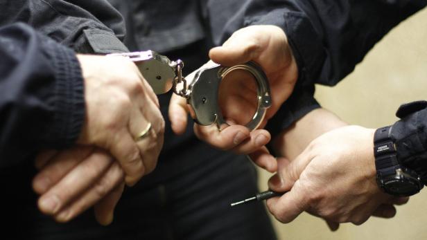 Eine Nahaufnahme von Handschellen, die angelegt werden.