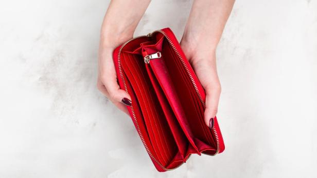 Rote, leere Geldtasche in Frauenhänden.