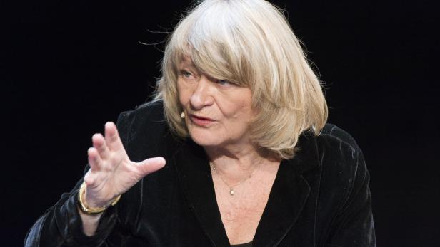 Eine Frau mit blonden Haaren gestikuliert während einer Präsentation.