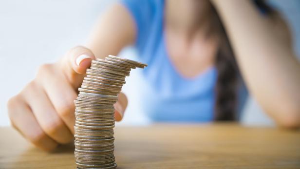 Eine Frau balanciert einen hohen Stapel von Münzen auf einem Tisch.