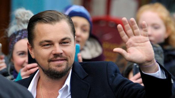 Leonardo DiCaprio winkt lächelnd in die Menge, während er von Fans umgeben ist.
