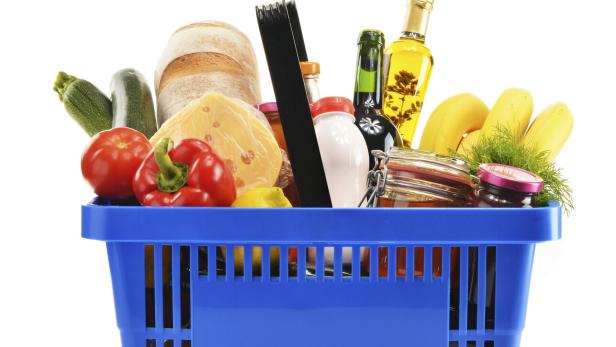 Shopping basket with variety of grocery products isolated on white