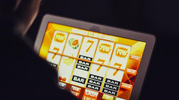 Gambling addicted man with glasses in front of online casino slot machine on laptop computer at night