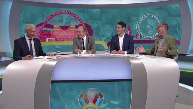 Vier Männer sitzen an einem Tisch vor einem Hintergrund mit Motiven der UEFA Euro 2020.
