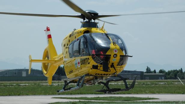 Ein gelber Rettungshubschrauber des ÖAMTC steht auf einem Flugfeld.