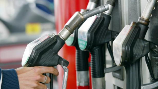 Eine Hand betätigt eine Zapfpistole an einer Tankstelle.