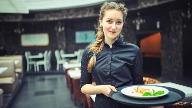 Waiters carrying plates with food, in a restaurant.