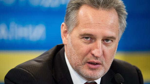 Ein Mann mit grauem Haar und Bart spricht vor einem blau-gelben Hintergrund.