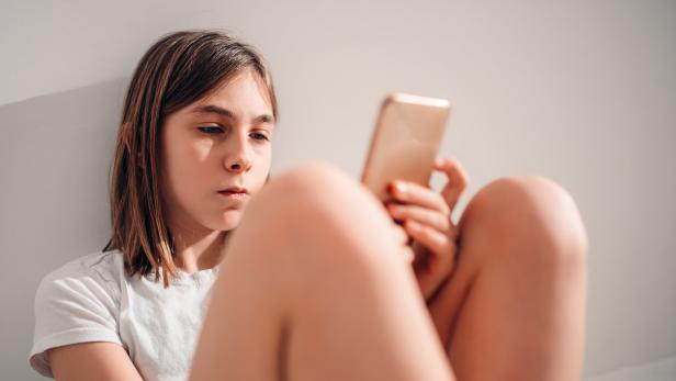Ein Mädchen schaut ins Smartphone.
