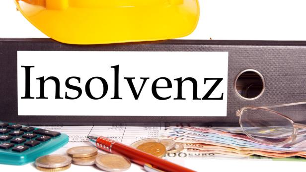 Ein gelber Bauhelm liegt auf einem Ordner mit dem Wort „Insolvenz“.