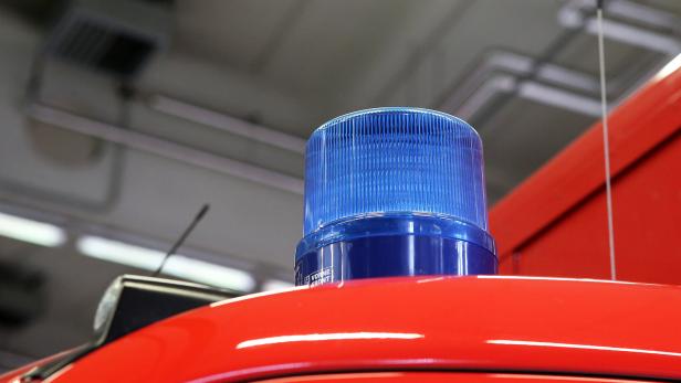 Ein rotes Feuerwehrauto mit eingeschaltetem Blaulicht.