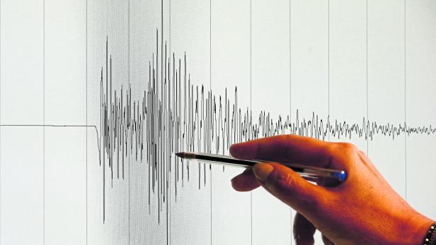Eine Hand deutet mit einem Stift auf eine seismografische Aufzeichnung eines „Erdbeben in Niederösterreich“.