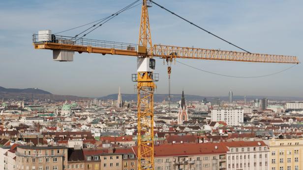 Ein gelber Baukran vor der Skyline von Wien.