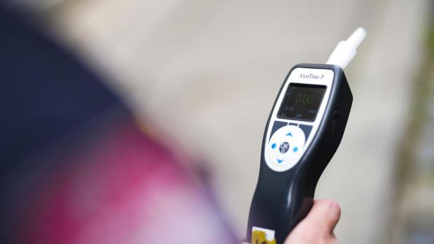 Eine Person hält ein Alcotrue P Alkoholmessgerät in der Hand.