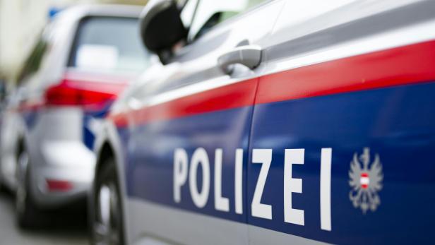 Zwei silberne Polizeiautos mit blau-rotem Streifen und dem Wort „Polizei“ stehen nebeneinander auf einer Straße.