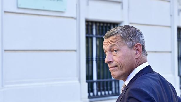 Der Mann steht vor dem Bundeskanzleramt, laut Aufschrift auf einem Schild.