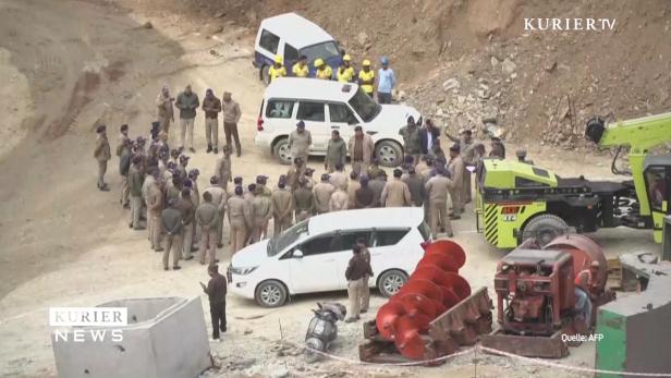 Eine Gruppe von Polizisten steht neben mehreren Fahrzeugen und Baumaschinen.