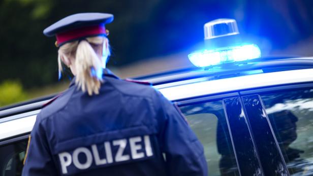 Polizistin vor Polizeiauto mit Blaulicht.