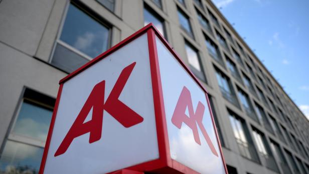 Ein Schild mit dem roten AK-Logo vor einem Bürogebäude.