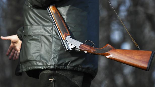 Ein Mann trägt ein offenes Jagdgewehr über der Schulter.