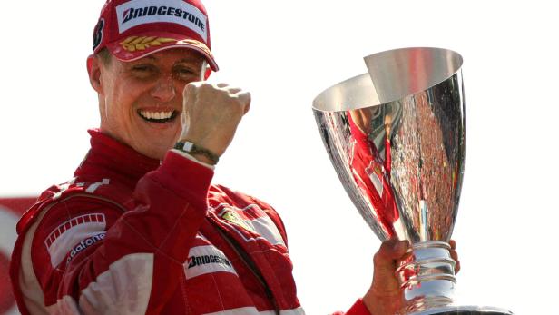 Michael Schumacher feiert mit der Siegestrophäe.