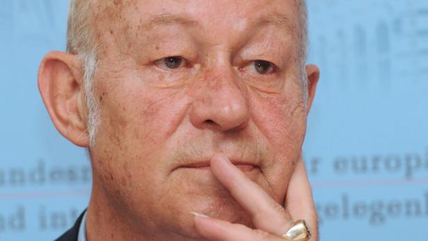 Ein Mann mit Anzug und Krawatte hält seine Hand ans Gesicht.