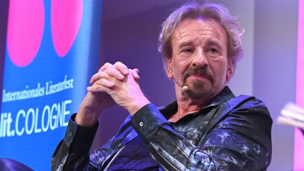 Thomas Gottschalk sitzt auf einer Bühne vor dem Logo des Internationalen Literaturfests lit.COLOGNE.