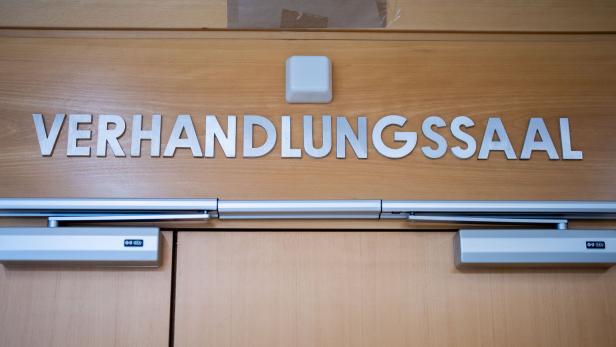 Über einer Holztür steht in großen silbernen Buchstaben das Wort „Verhandlungssaal“.