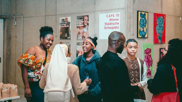 Eine Gruppe von Menschen steht in einem Raum mit Kunstwerken an der Wand.