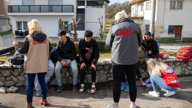 Helfer von Hilfsorganisationen kümmern sich um eine Gruppe von Menschen im Freien.