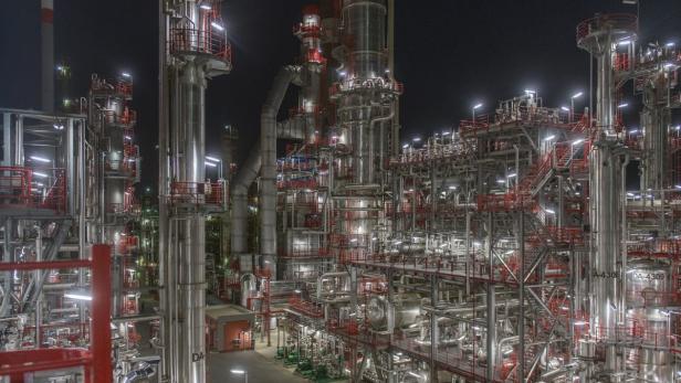 Eine nächtliche Aufnahme einer großen Industrieanlage mit vielen Rohren und Treppen.