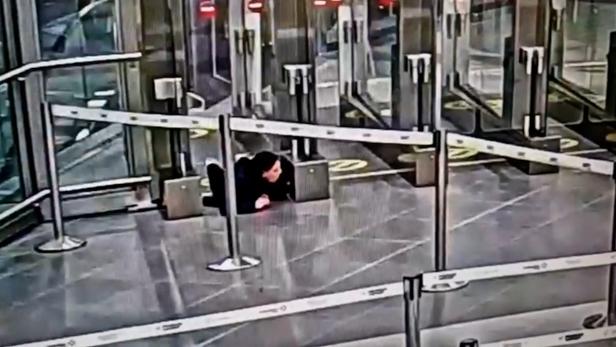 Eine Frau kriecht unter einem Absperrband hindurch.