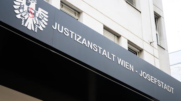 Schriftzug „Justizanstalt Wien - Josefstadt“ und ein stilisierter Adler an einer Gebäudefassade.