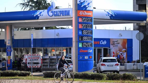 Eine Frau fährt mit dem Fahrrad an einer Gazprom-Tankstelle vorbei.