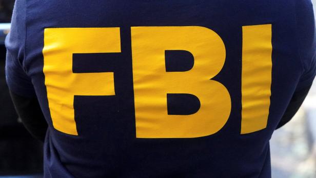 Große gelbe Buchstaben „FBI“ auf dunkelblauem Stoff, vermutlich auf dem Rücken einer Jacke.
